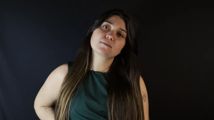 A mesma pessoa dos retratos, em movimento diante do fundo escuro do estúdio: ela vira o rosto e olha para a câmera