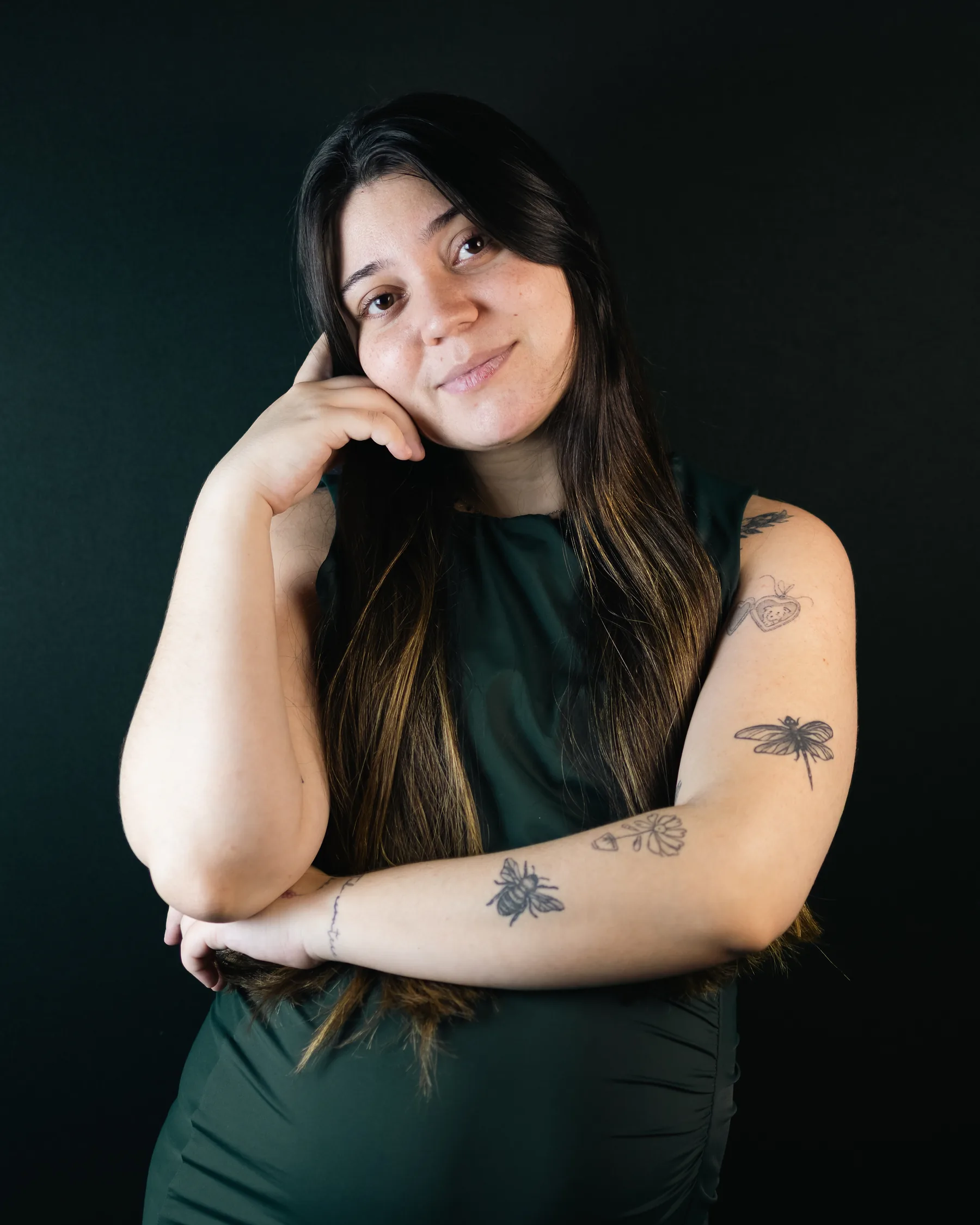 Retrato de estúdio: a mesma mulher com a mão apoiada no rosto e os braços dobrados, sorrindo para a câmera