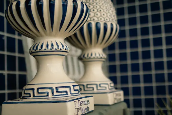 Par de fruteiras de faiança branca com friso azul, diante da parede de azulejos