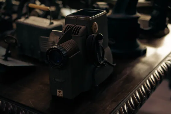 Projetor de cinema antigo sobre a mesa entalhada, na penumbra