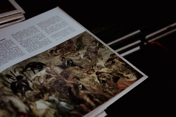Livro aberto sobre a mesa, com a reprodução de uma pintura clássica