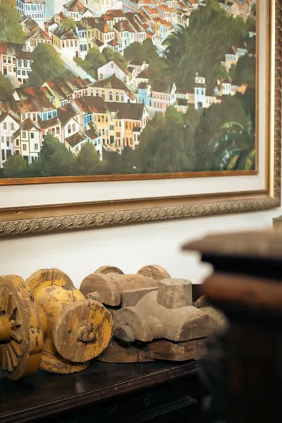 Quadro de uma cidade de casario colorido na encosta, com rodas de madeira embaixo