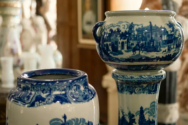 Cachepôs de porcelana branca com cenas azuis, sobre coluna