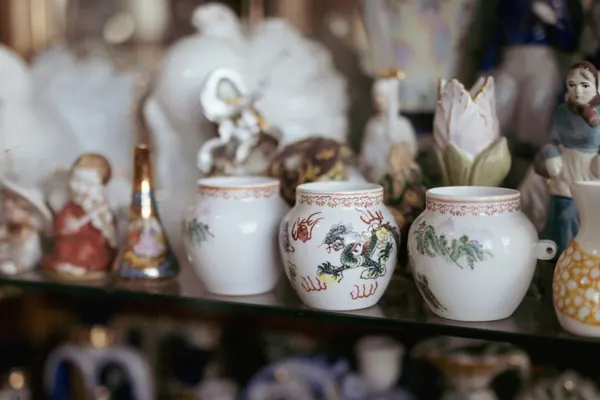 Prateleira de vidro com estatuetas de porcelana, potes chineses e figuras