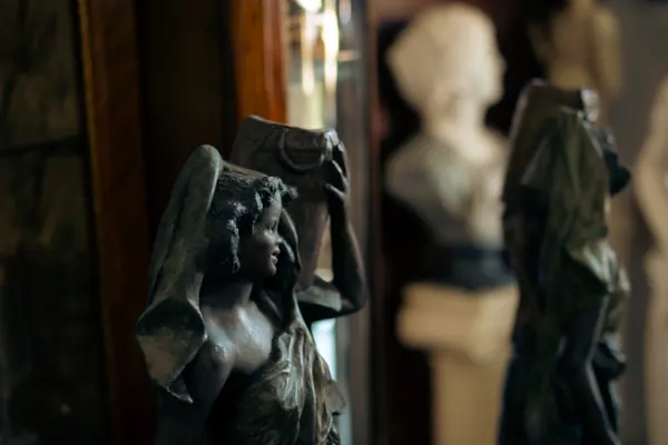 Estátua de bronze de uma figura feminina com manto, entre outras peças