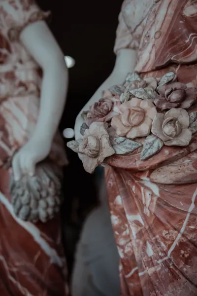 Figura de mármore rosado segurando um ramo de rosas esculpidas