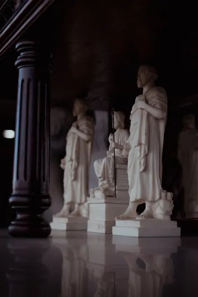 Estatuetas brancas alinhadas sobre o balcão brilhante, com o reflexo embaixo