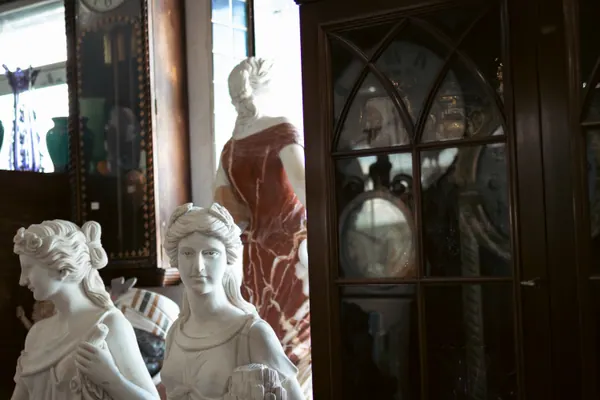 Estátuas de mármore ao lado de um armário envidraçado, na luz da janela