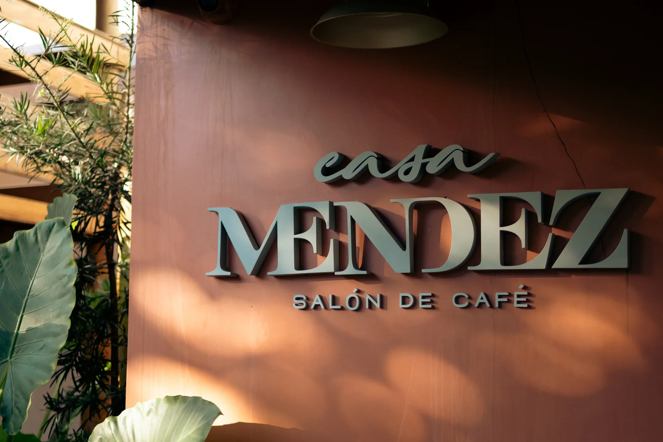 Letreiro em relevo com o nome Casa Mendez, salón de café, sobre a parede terracota