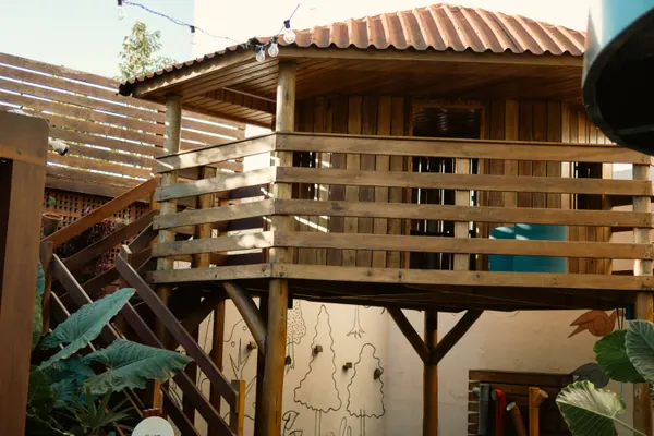 Casinha de madeira suspensa com telhado de telha, sobre a parede pintada