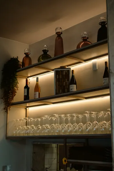 Prateleira iluminada com garrafas de vinho e fileiras de taças de cabeça para baixo
