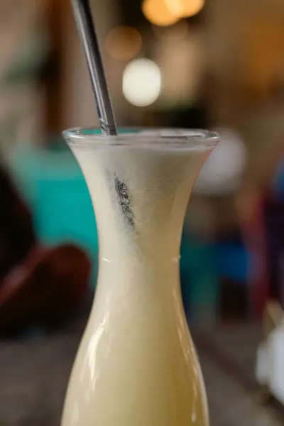 Jarra de limonada com canudo de metal, com o salão desfocado atrás
