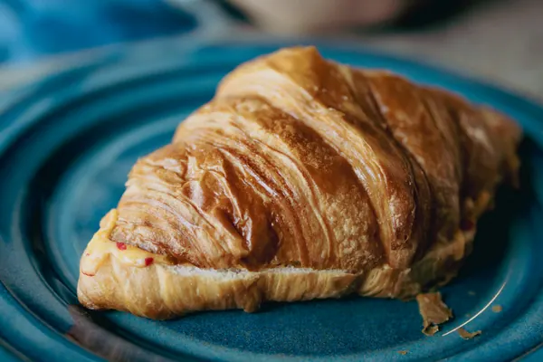 Outro croissant no prato azul, visto de lado