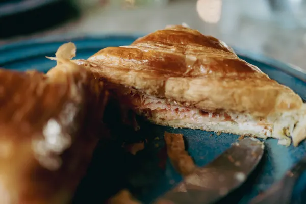 Croissant aberto ao meio, mostrando o recheio de presunto e queijo