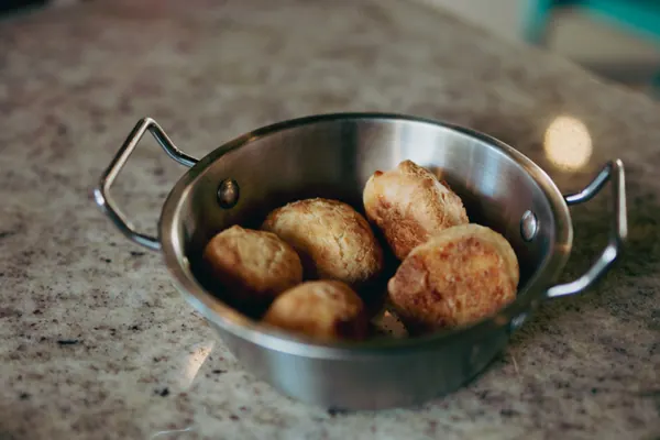 Bolinhos fritos dourados servidos numa frigideira pequena de metal