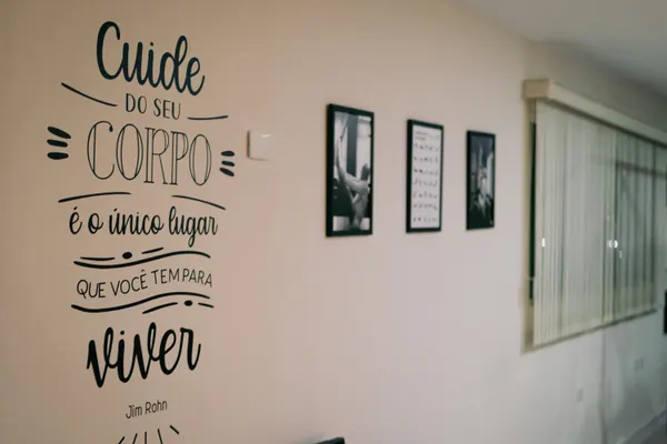Parede com a frase “Cuide do seu corpo, é o único lugar que você tem para viver”, e quadros ao lado
