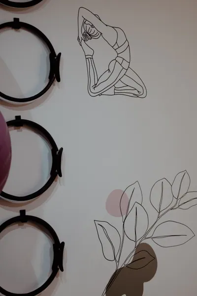 Arcos flexíveis pretos pendurados na parede, ao lado do desenho de uma figura alongando