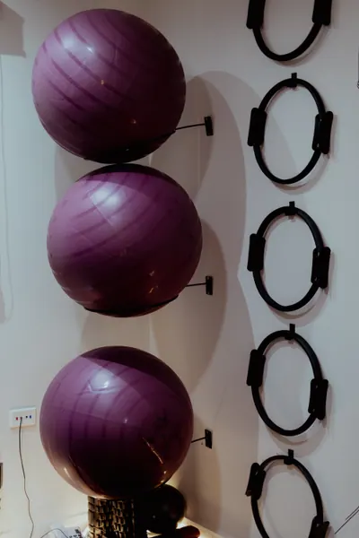 Três bolas de pilates roxas encaixadas em suportes na parede, ao lado dos arcos