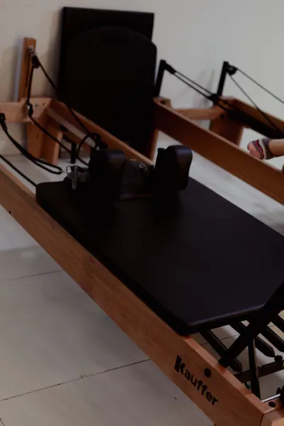 Aparelho de pilates reformer de madeira e estofado preto, visto de perto