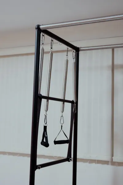 Cadillac de pilates vazio, com as alças e as molas paradas contra a persiana