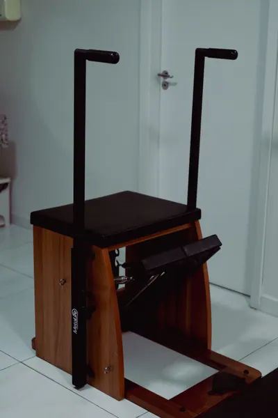 Cadeira de pilates de madeira com apoios pretos, junto à porta da sala