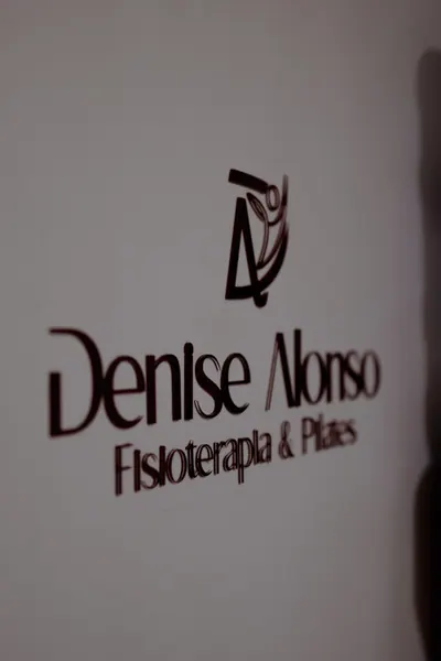 A logo em relevo na parede, de perto, com a sombra que ela projeta