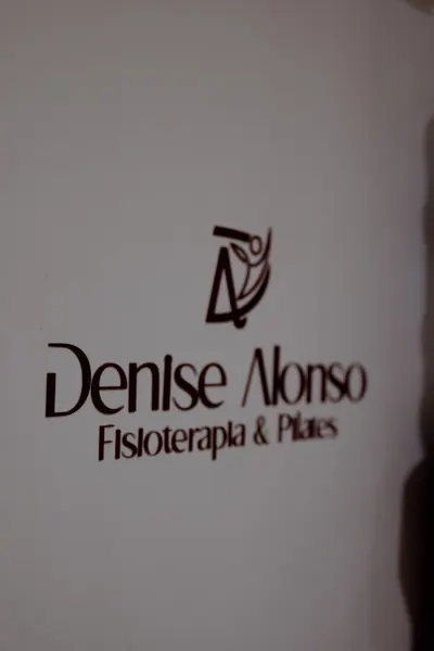 Logo em relevo na parede branca com o nome Denise Alonso, fisioterapia e pilates